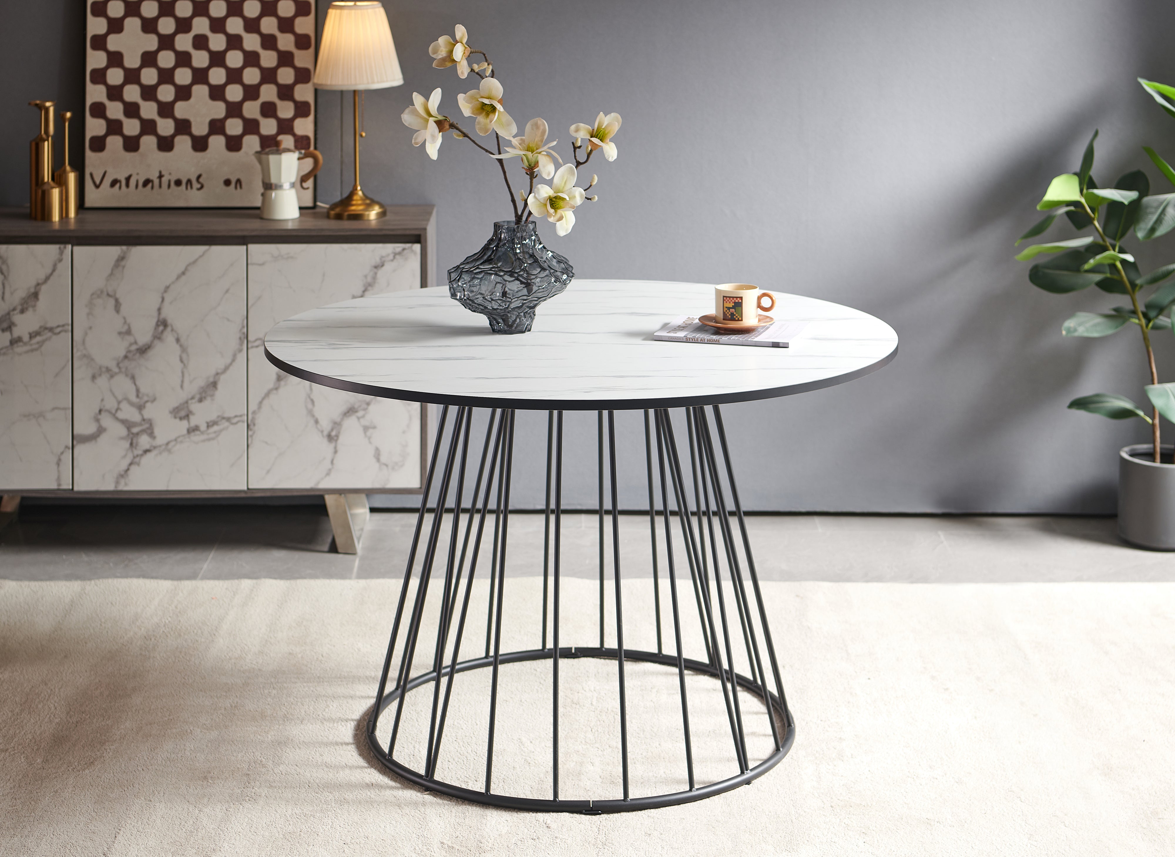 Mesa de comedor redonda Stella con efecto mármol blanco y base de metal negro.