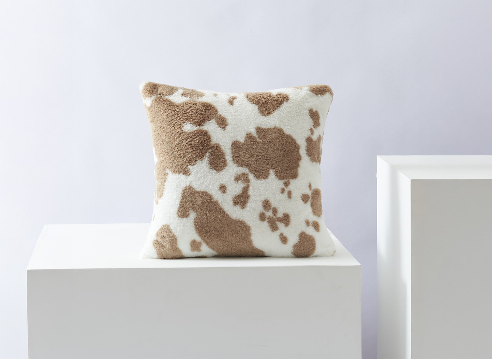 Cojín cuadrado SAKINA de 45x45 cm en tejido de pelo con efecto piel de vaca en color topo y blanco.