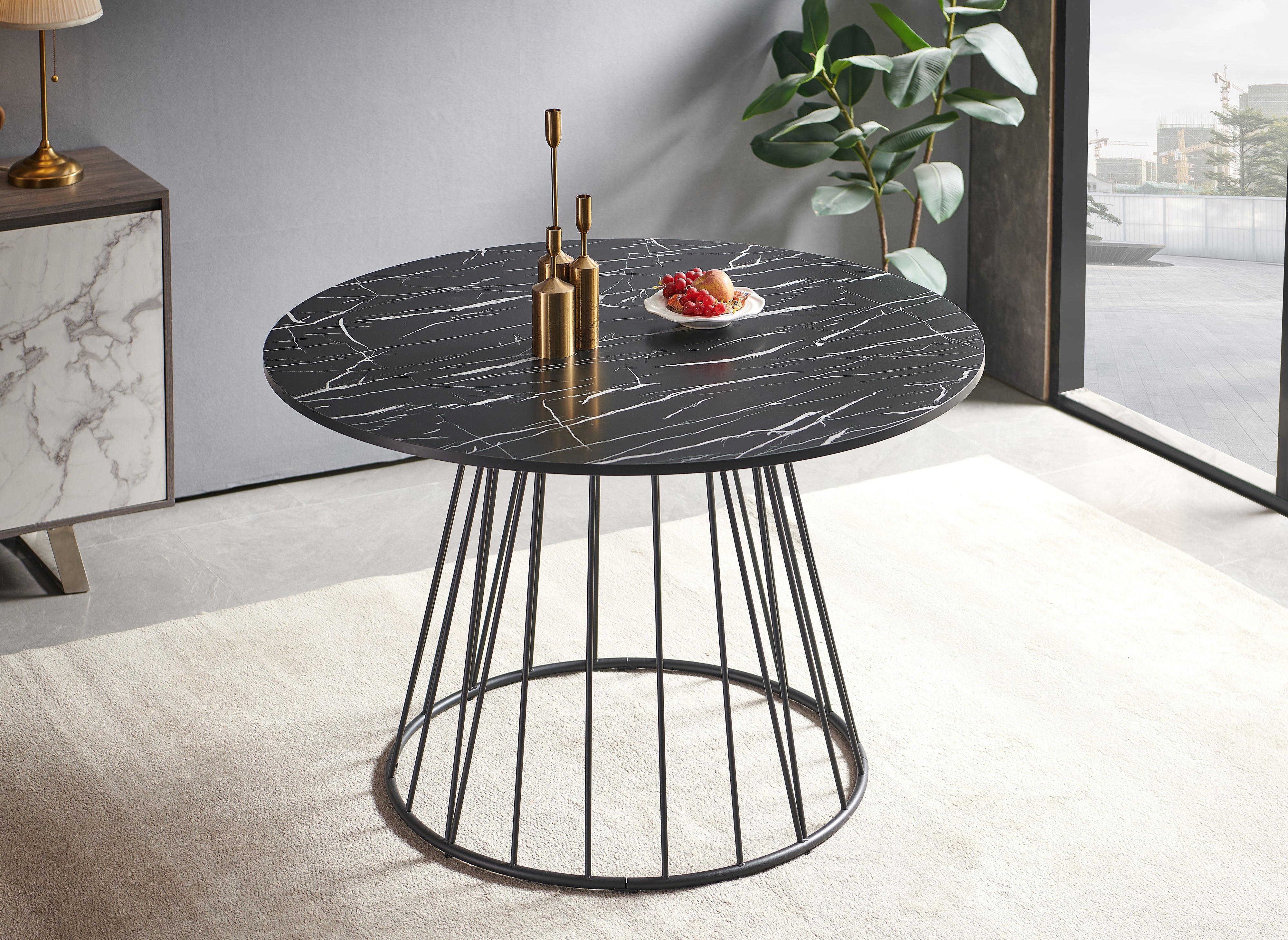 Mesa de comedor redonda Stella con efecto mármol negro y base de metal negro.